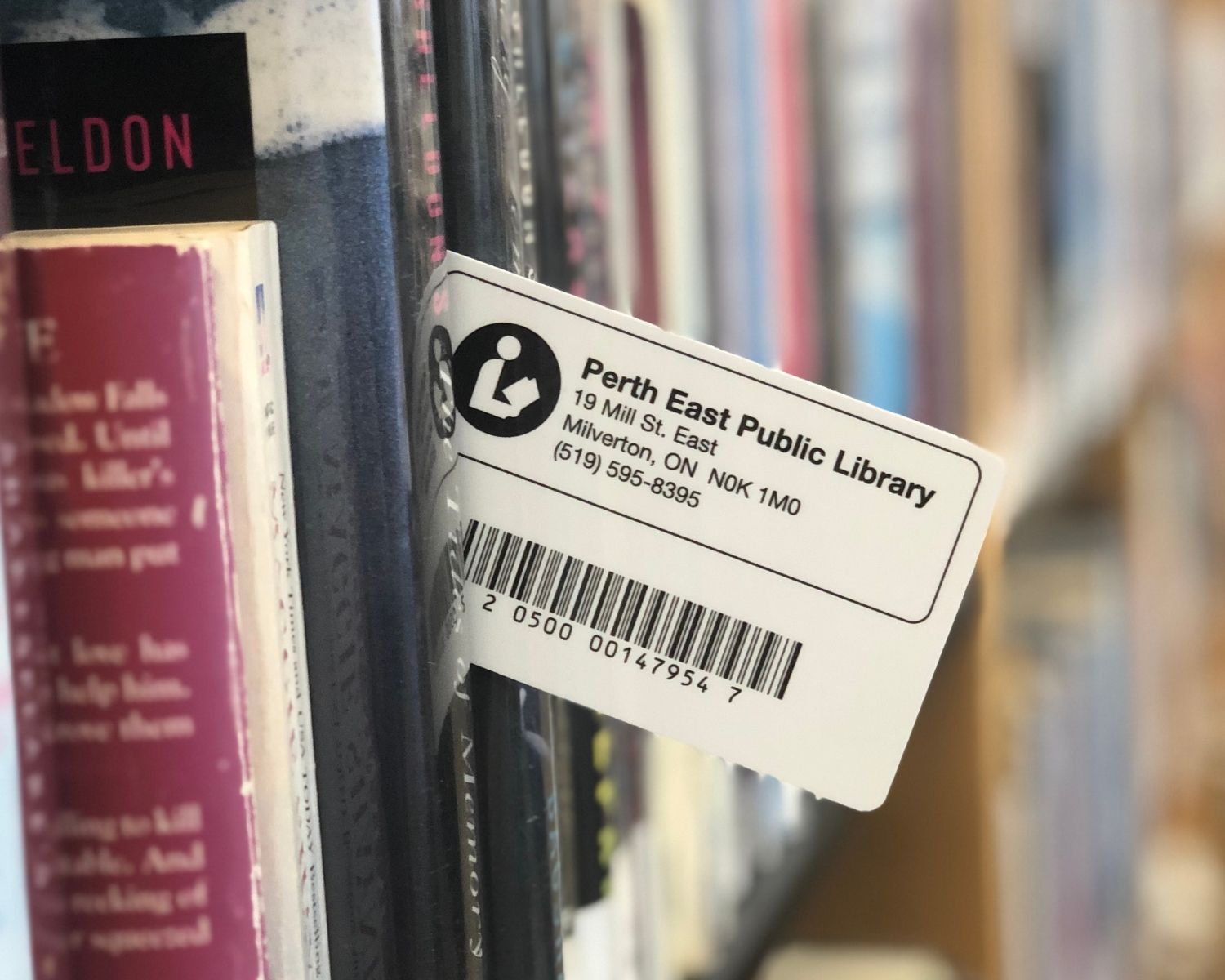 A Perth East Public Library card slid within a book shelf