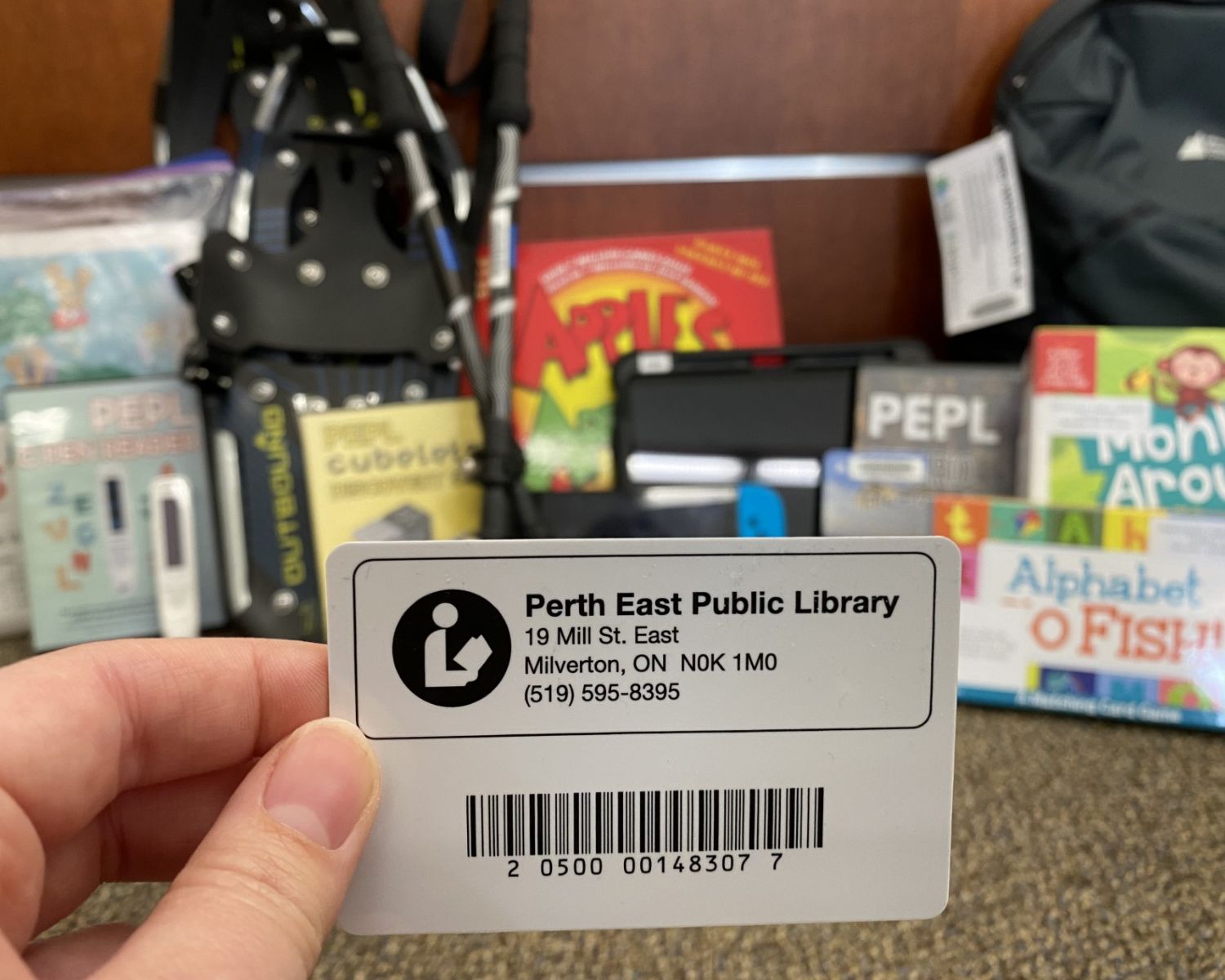 A picture of a PEPL library card with the PEPL Library of Things catalogue in the background