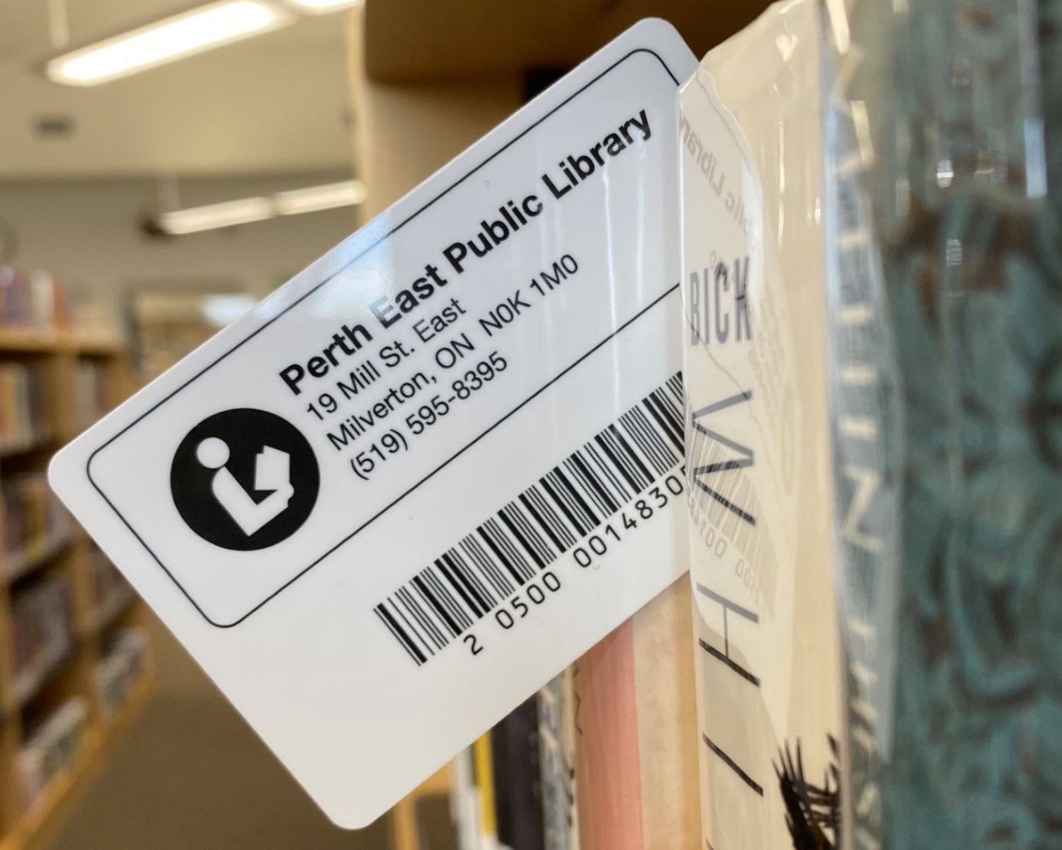 A PEPL library card held within books on the library shelves