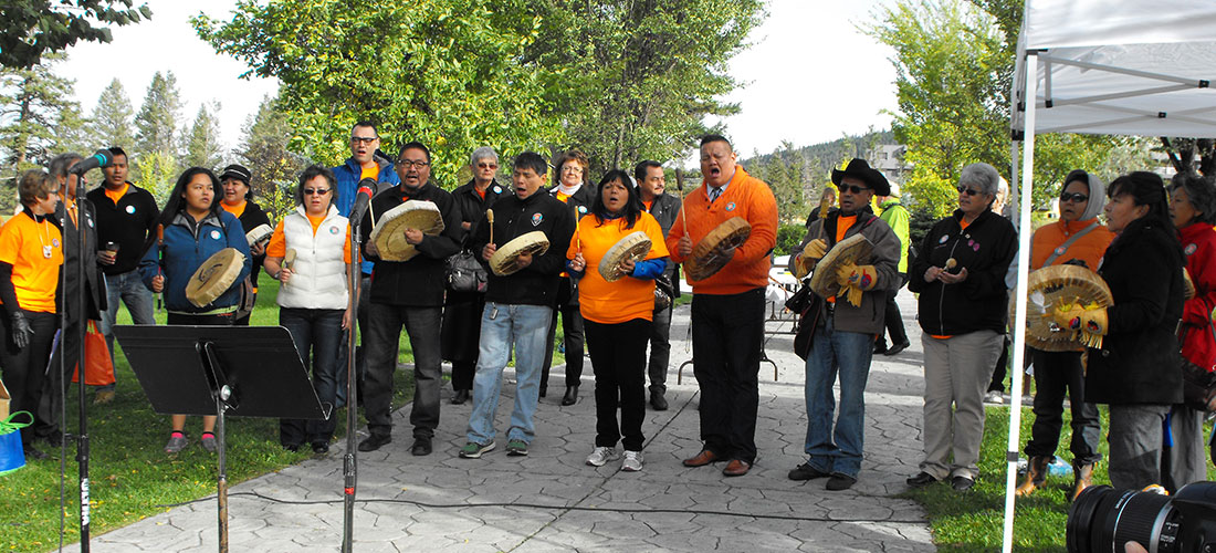 People gathered for orange shirt day who are drumming