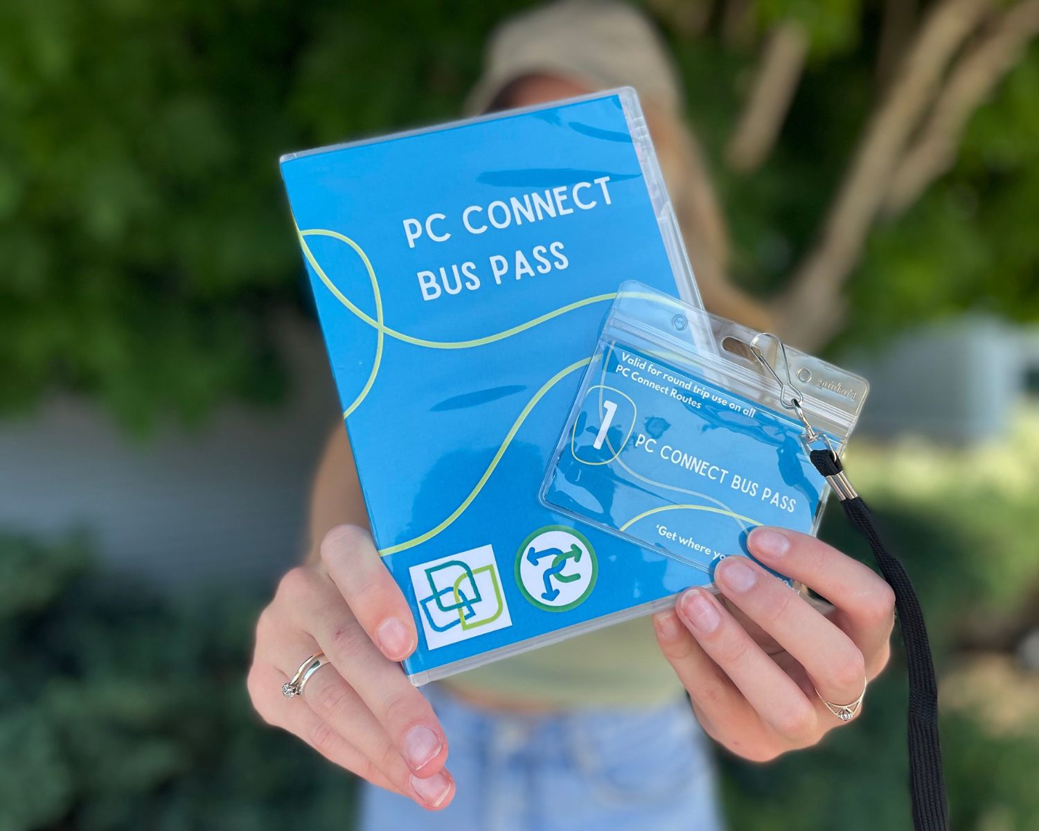 A person holding A PC Connect Bus Pass with a tree in the background